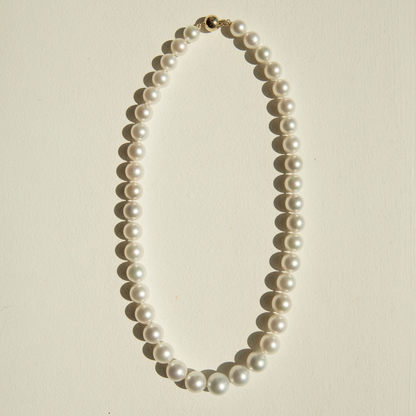 Pearl strand necklace on a beige background