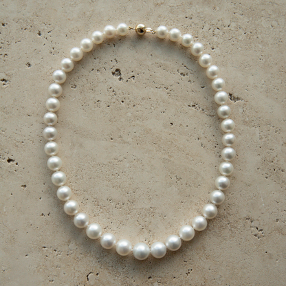 Pearl strand necklace on a textured beige surface