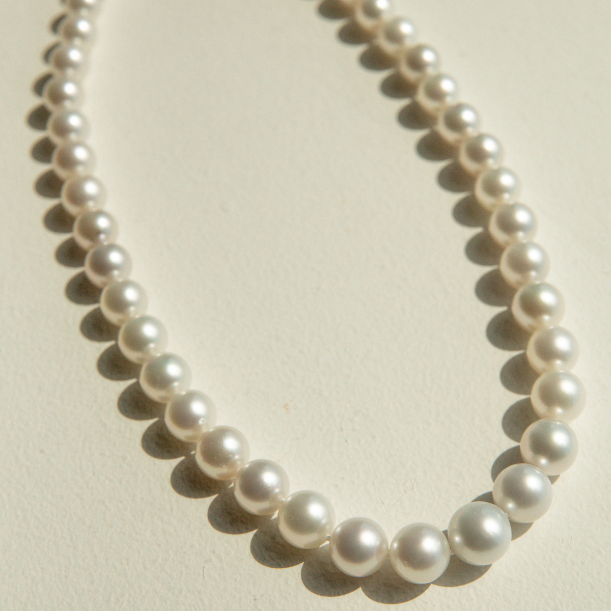 Pearl strand necklace on a light beige background