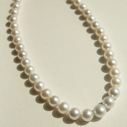 Pearl strand necklace on a light beige background