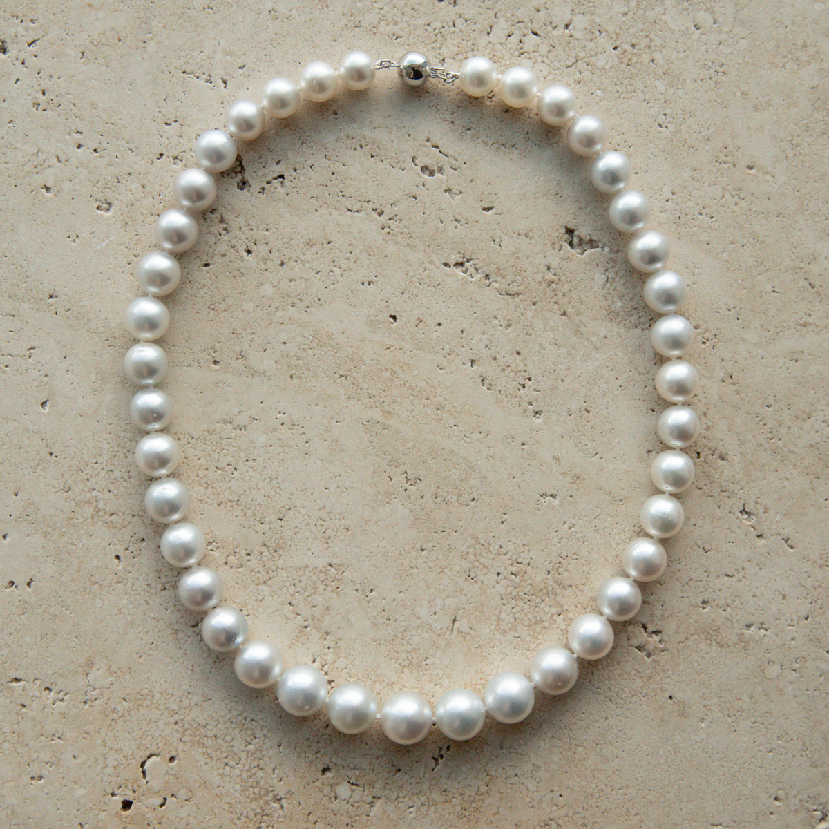 Pearl strand necklace on a textured beige surface