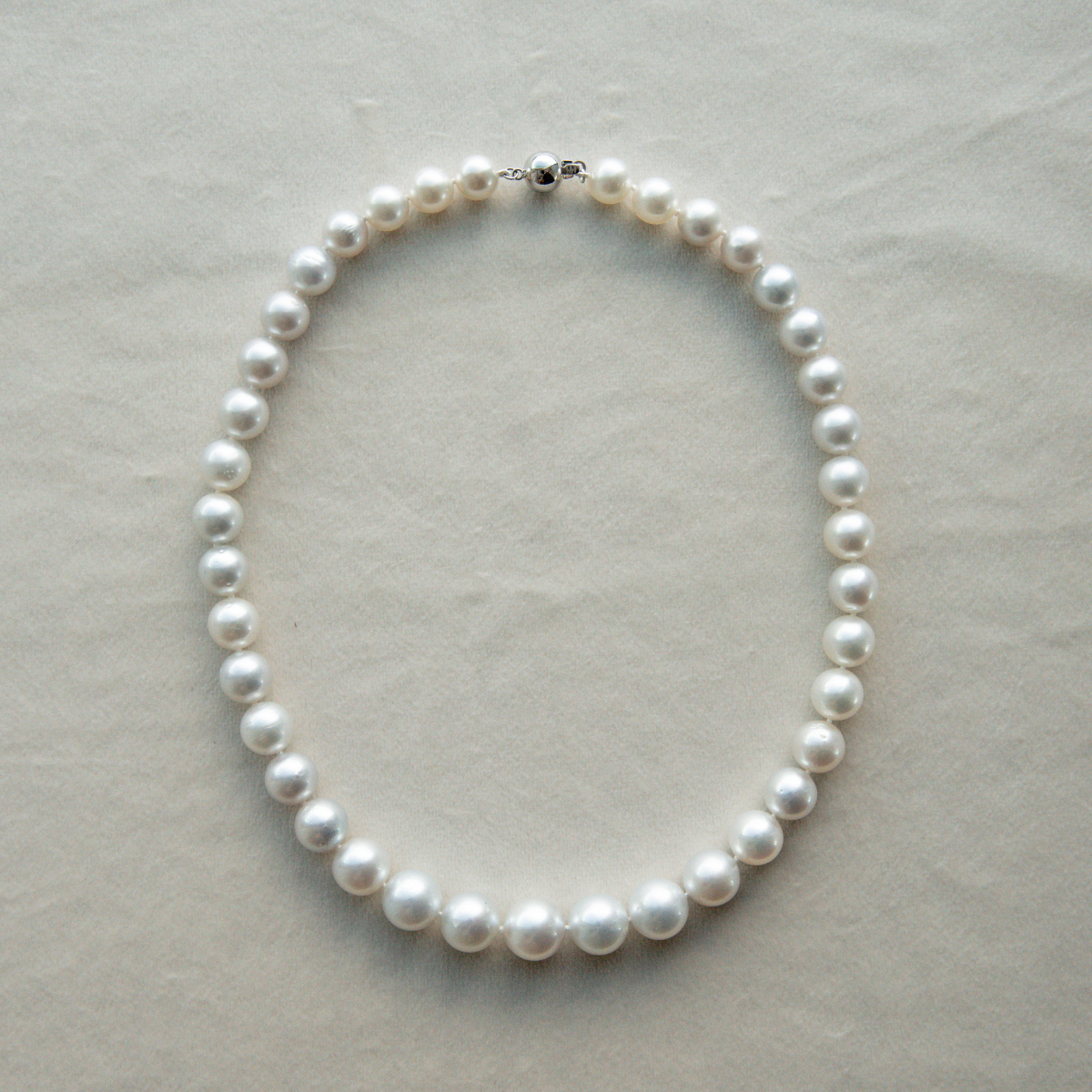 Pearl strand necklace on a light gray background
