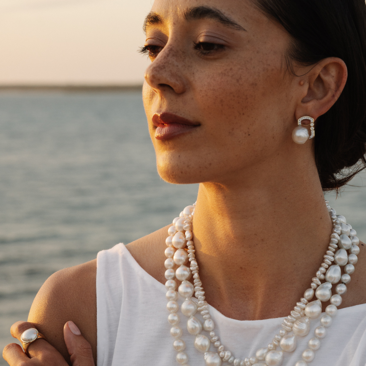 Woman wearing pearl jewelry by a body of water