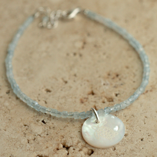 A unique Mother of Pearl charm bracelet featuring aquamarine gemstone beads, set in sterling silver.