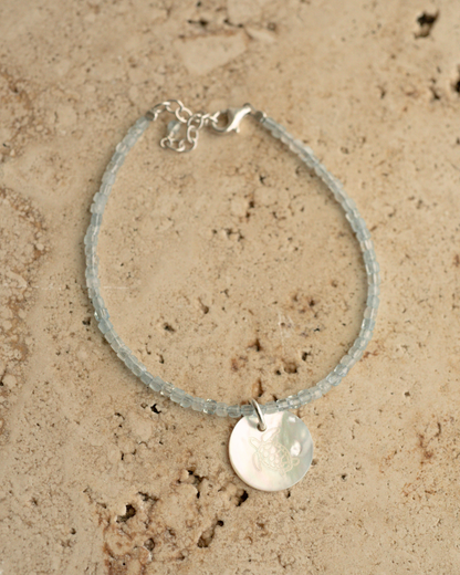 A unique Mother of Pearl charm bracelet featuring aquamarine gemstone beads, set in sterling silver.