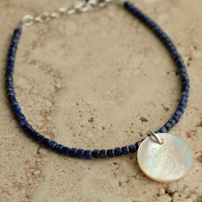 A unique Mother of Pearl charm bracelet featuring lapis lazuli gemstone beads, set in sterling silver.