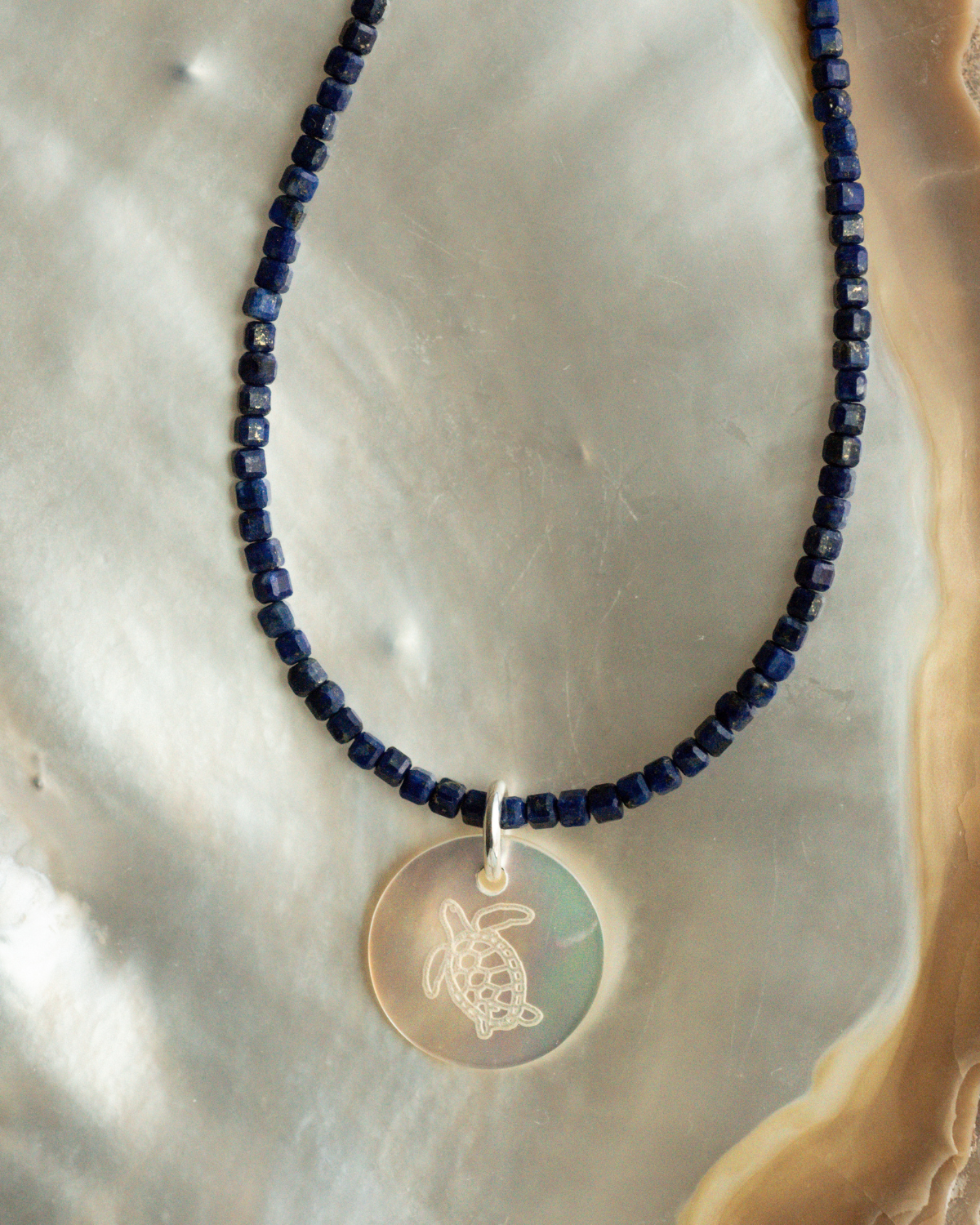 A unique Mother of Pearl charm bracelet featuring lapis lazuli gemstone beads, set in sterling silver.