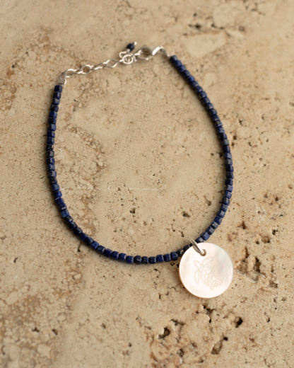 A unique Mother of Pearl charm bracelet featuring lapis lazuli gemstone beads, set in sterling silver.