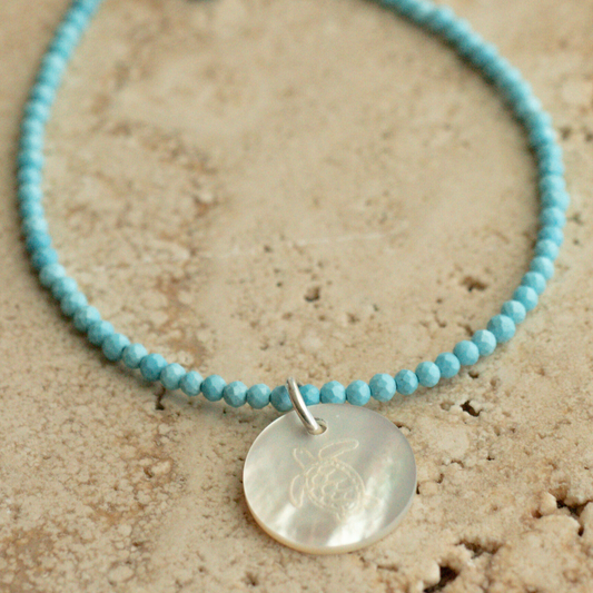 A unique Mother of Pearl charm bracelet featuring turquoise gemstone beads, set in sterling silver.