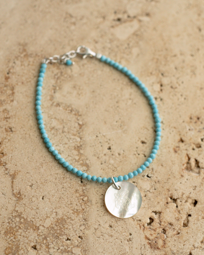 A unique Mother of Pearl charm bracelet featuring turquoise gemstone beads, set in sterling silver.