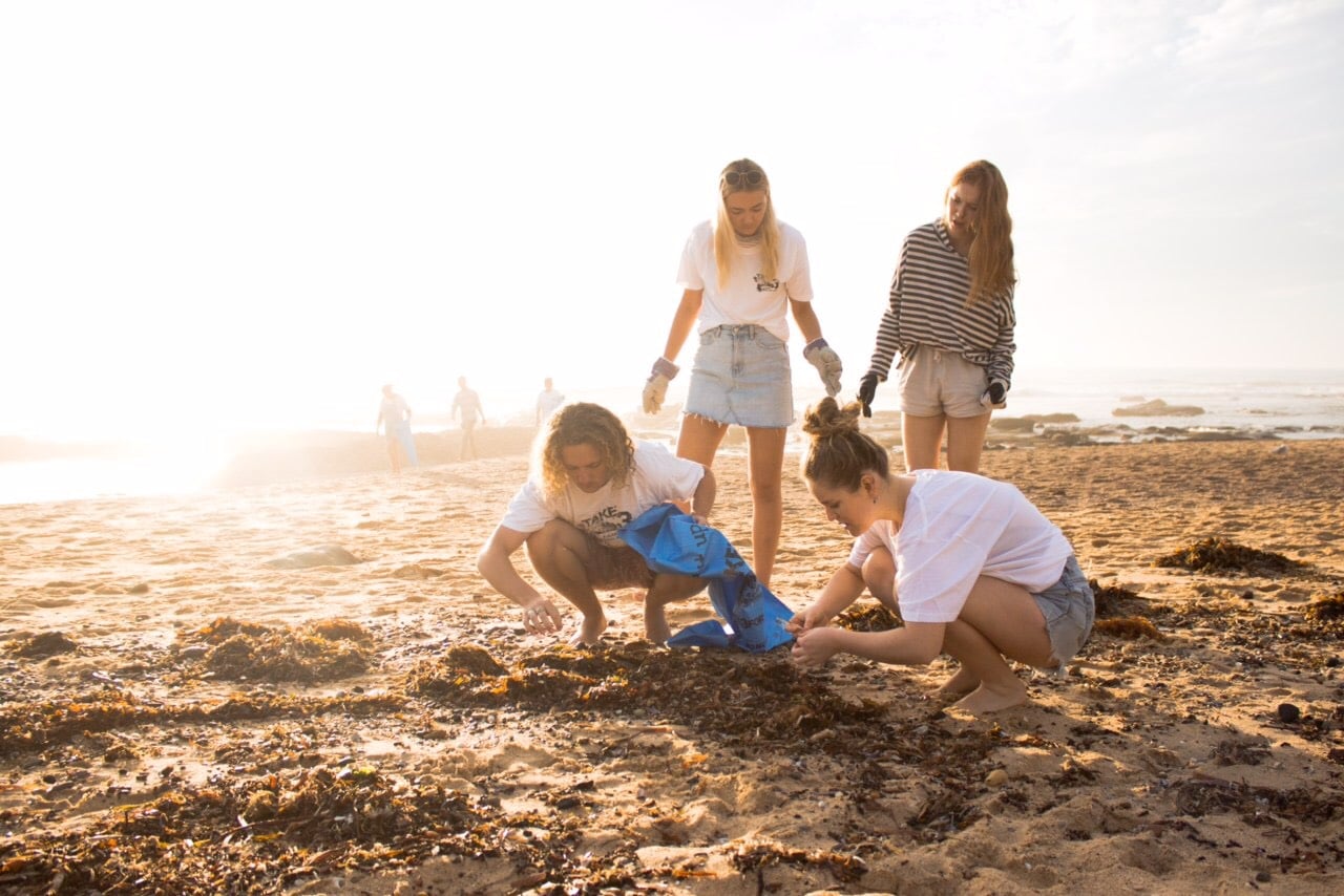 A group of people taking three pieces of rubbish each from the coastline, part of the important initiative of Take 3 for the Sea. 