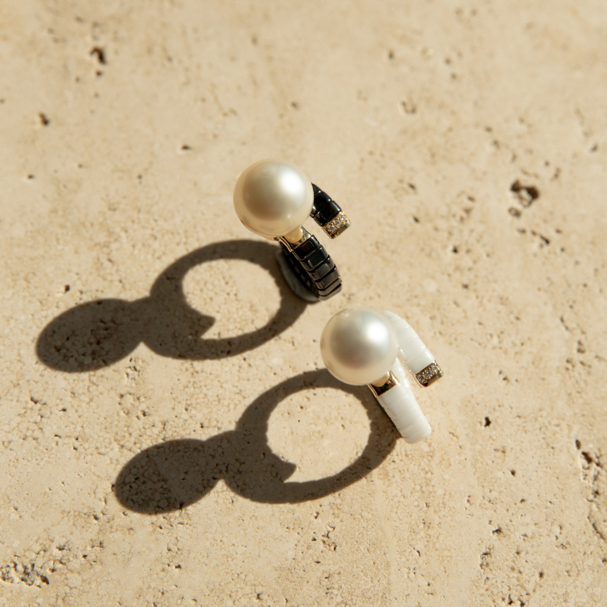 Two black and white ceramic rings with stunning South Sea pearls, set on a stone.