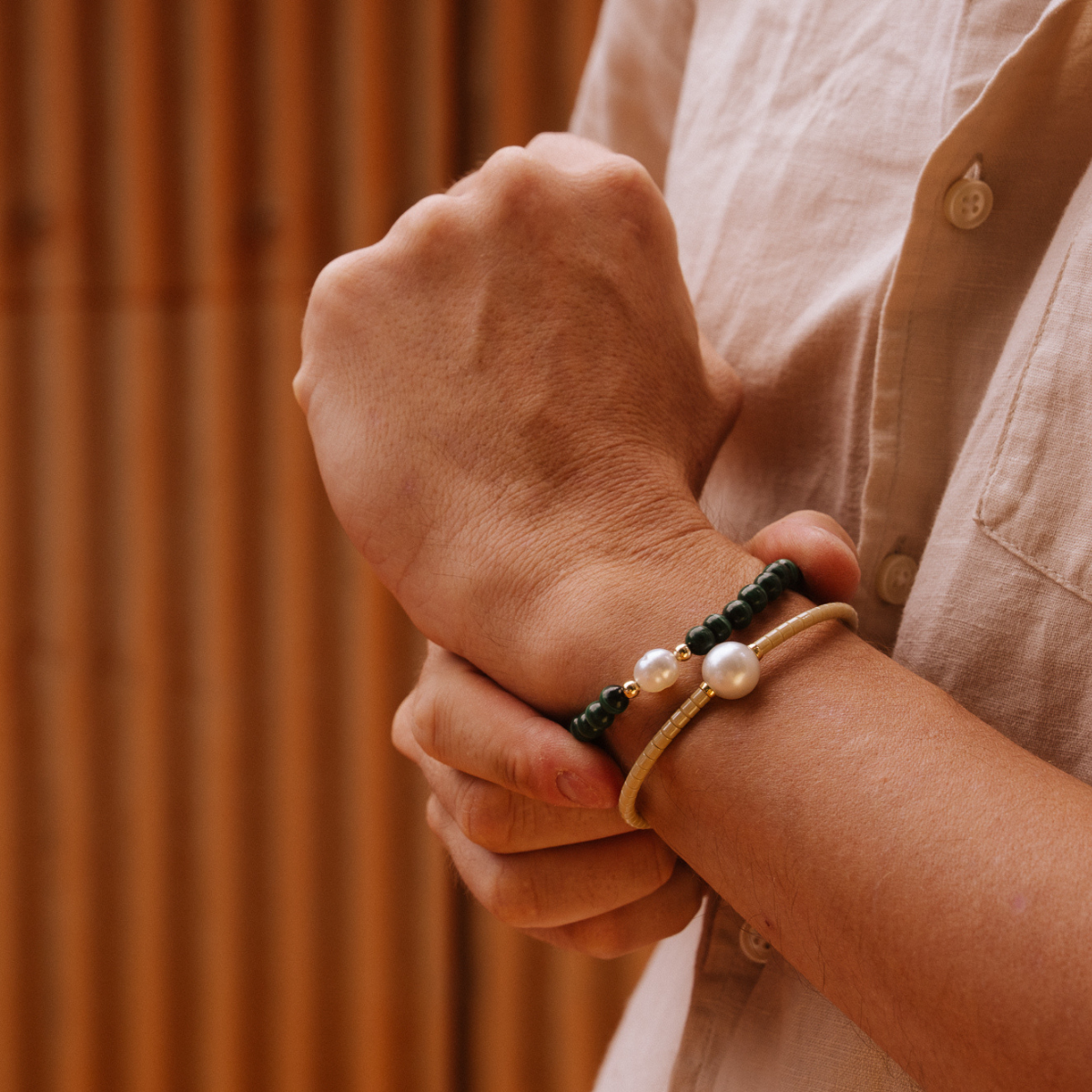 Close-up of a person's wrist with multiple bracelets against a blurred background