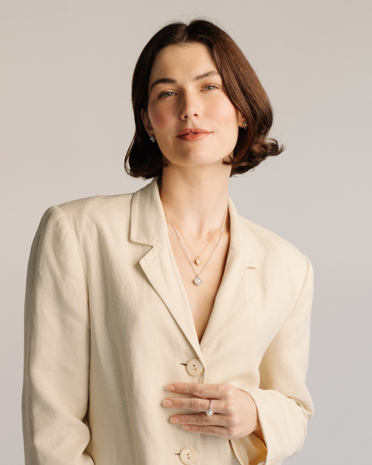 Woman wearing a light-colored blazer against a plain background, with a hypoallergenic pearl jewellery set that includes a range of pieces from our Kimberley Lily collection featuring our Australian South Sea Keshi pearls.