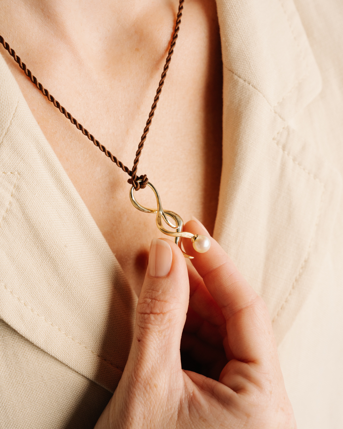 Necklace with a uniquely designed Australian Akoya pearl pendant held by a hand against a neutral background, a perfect hypoallergenic jewellery option.
