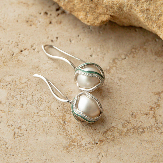 Pearl earrings on a textured beige surface