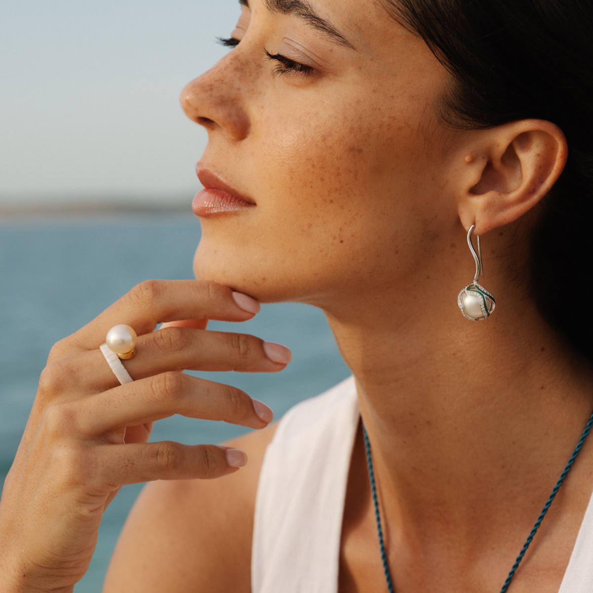 Woman wearing pearl earrings and ring with a blurred background