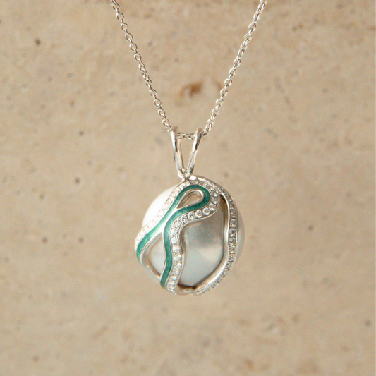 Silver necklace with a pearl pendant featuring a green and white design on a beige background