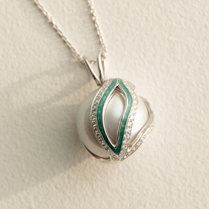 Silver pearl pendant with green accents on a light beige background