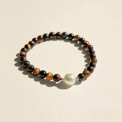 Bracelet with multicolored tiger eye beads and a pearl on a beige background