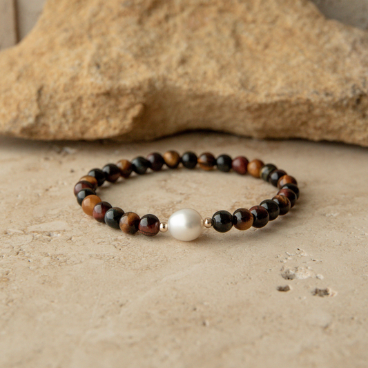 Tiger eye beaded bracelet with a pearl on a stone surface