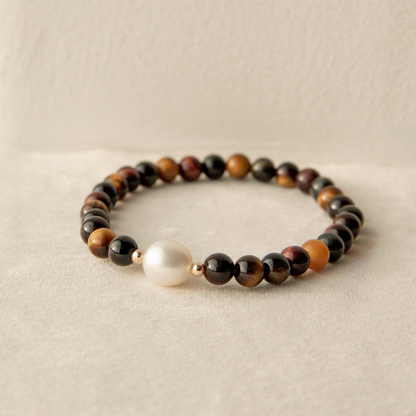 Tiger eye beaded bracelet with a pearl on a beige background