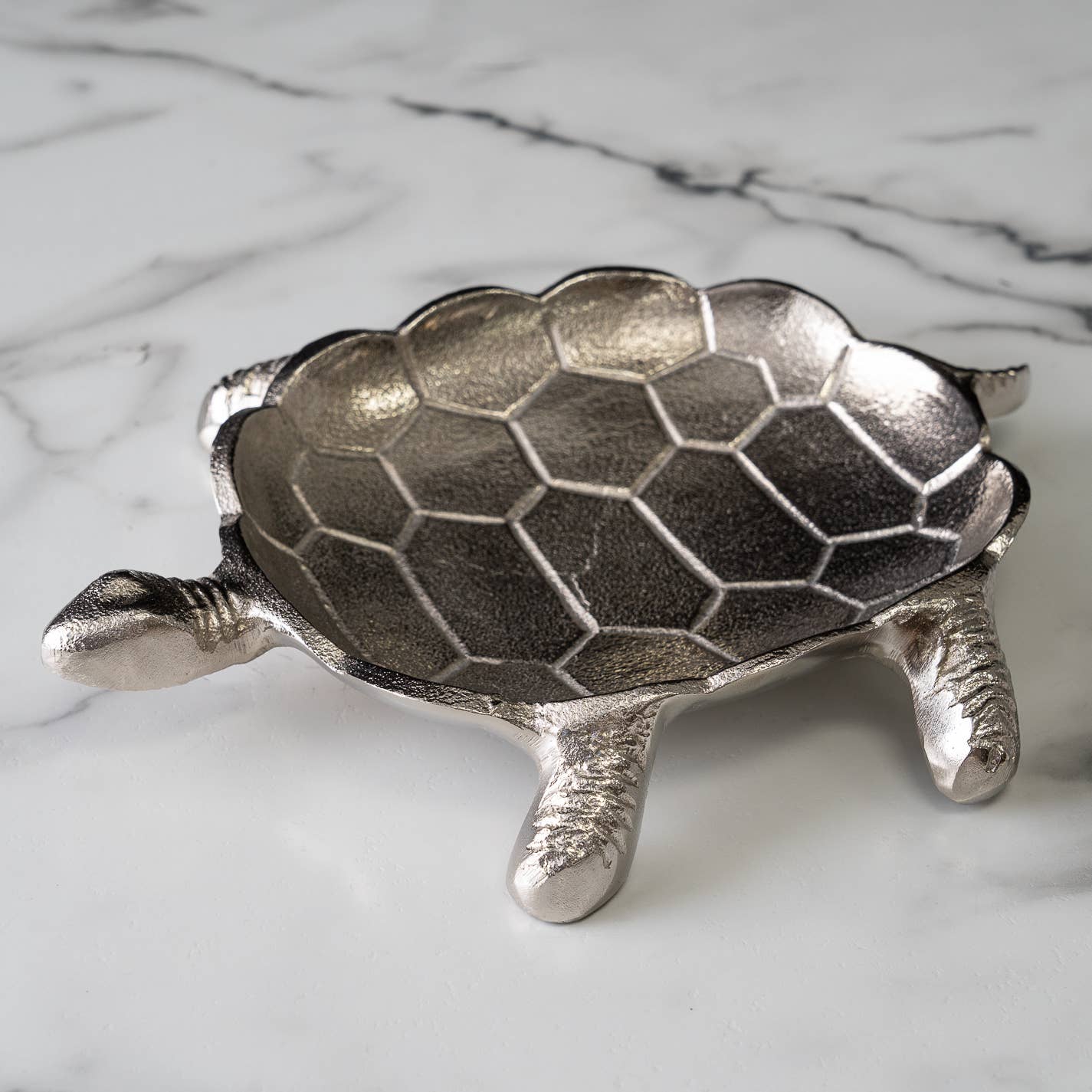 Metallic turtle-shaped dish on a marble surface