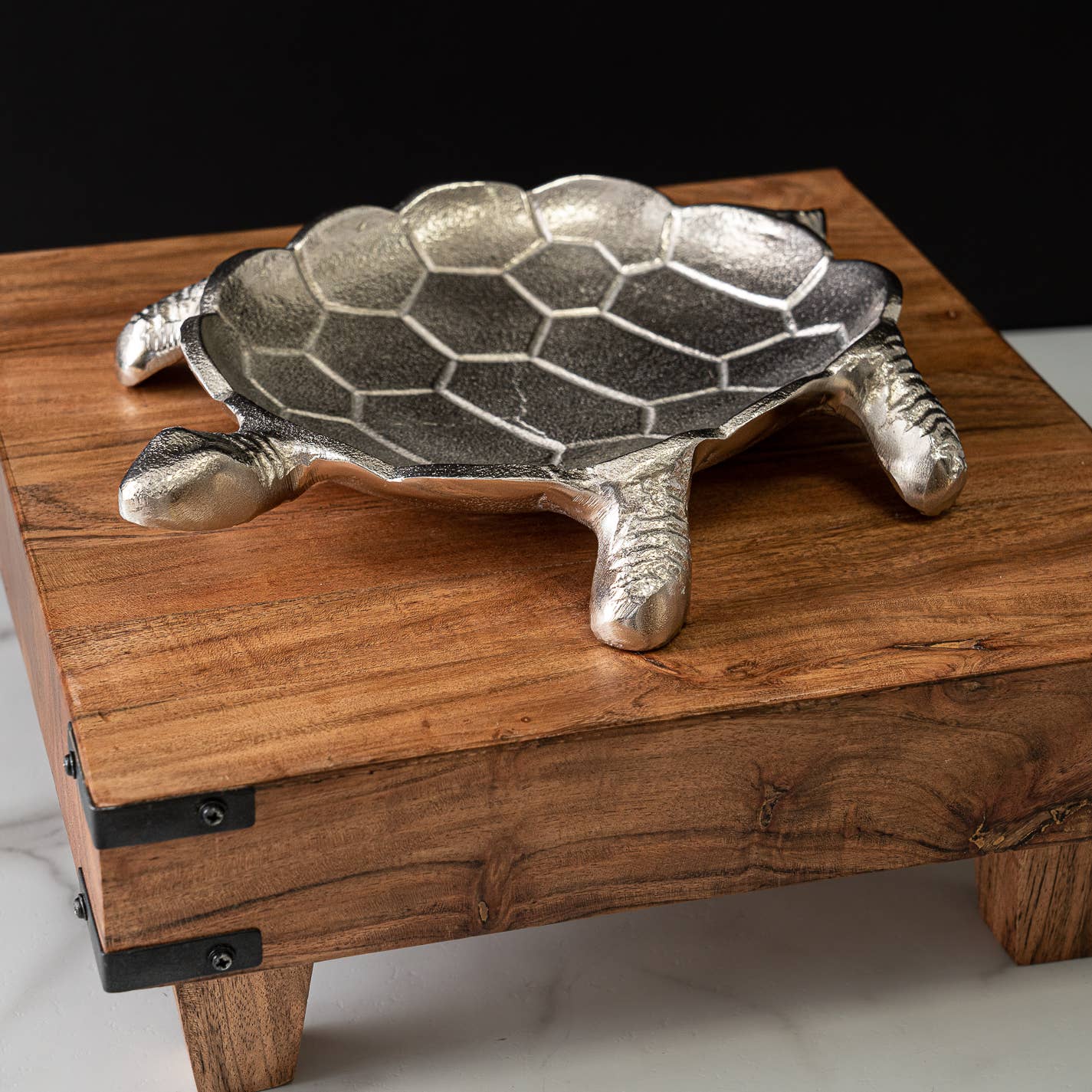 Metal turtle sculpture on a wooden platform