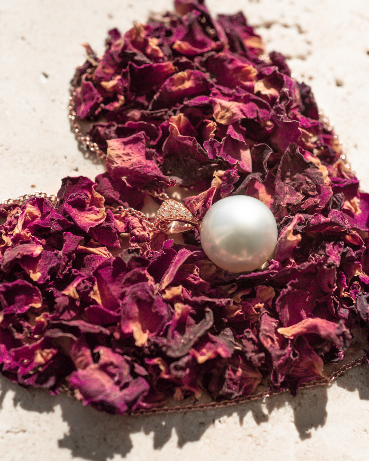 Purple dried flower arrangement with a pearl pendant in the center on a light background