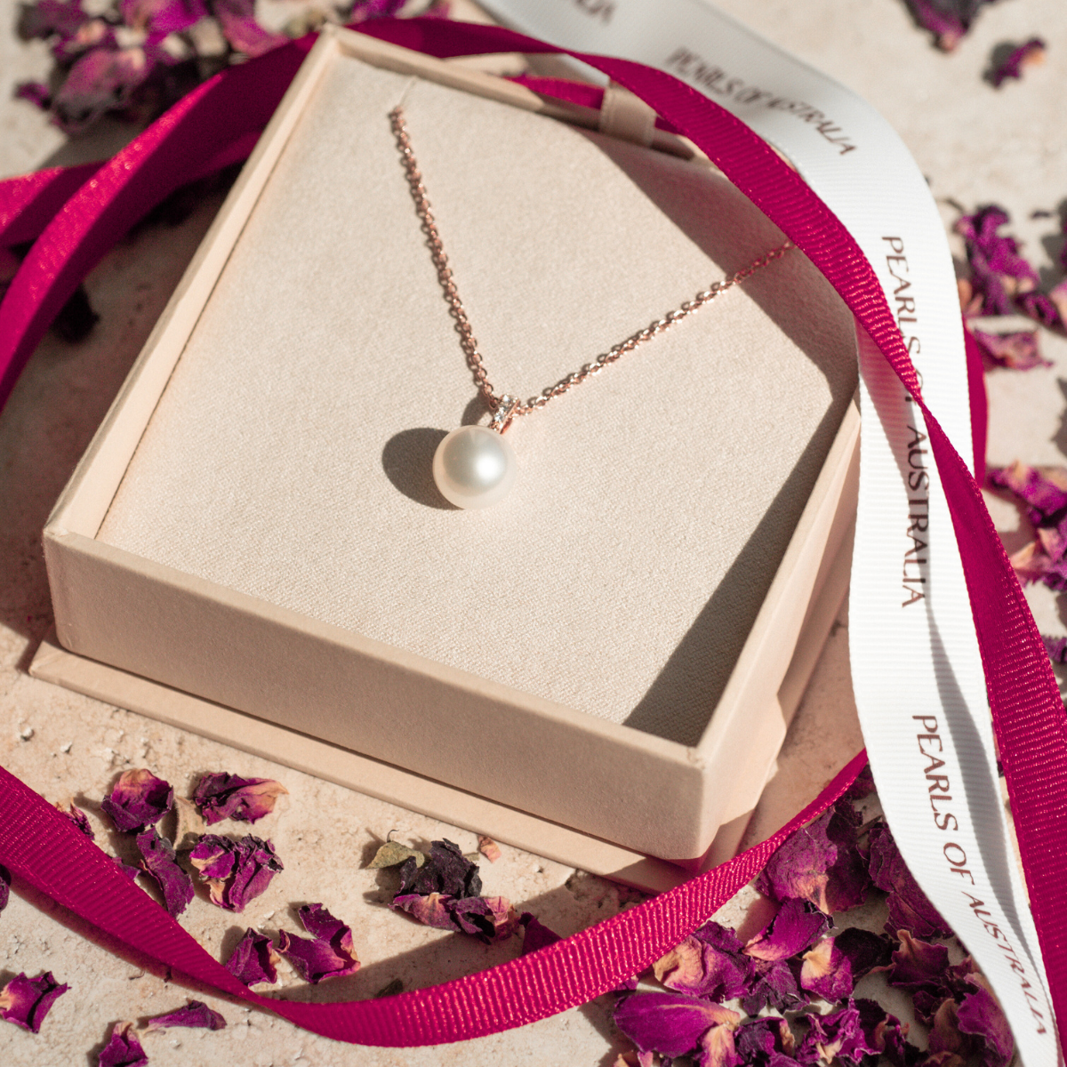 Pearl necklace in a jewelry box with pink ribbon and dried flowers