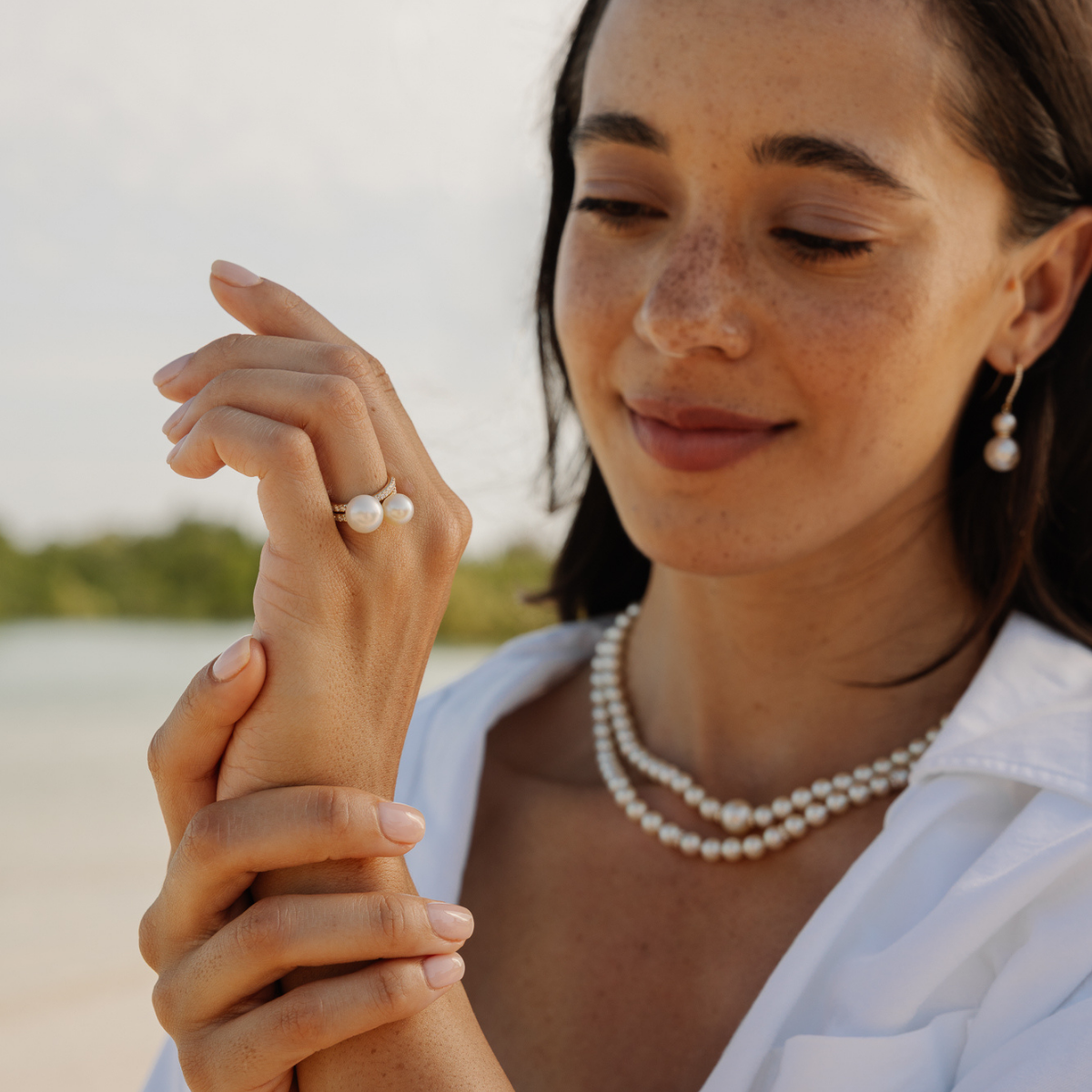 Woman wearing a pearl necklace, pearl rings and pearl hooks outdoors