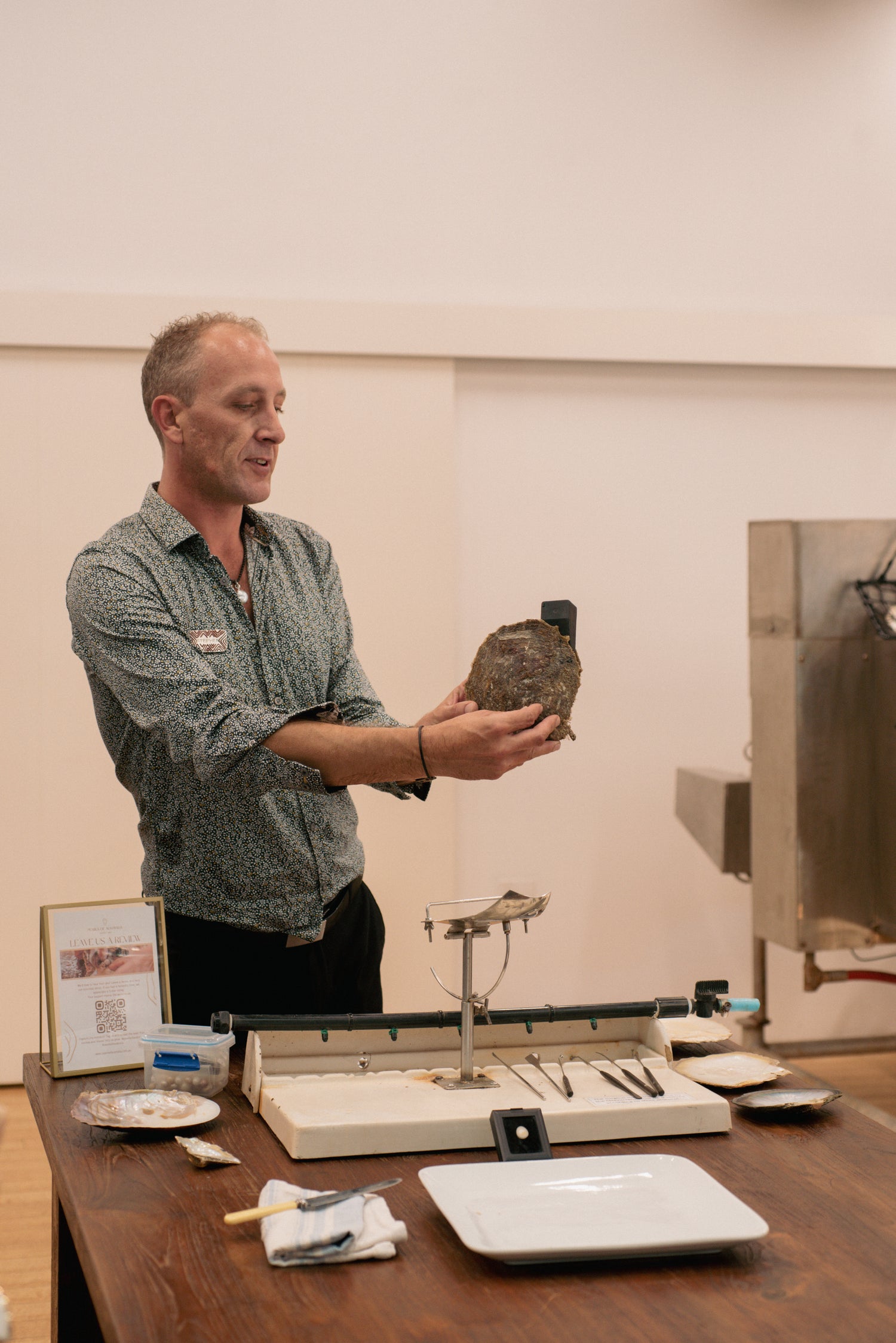 One of our pearl experts in the midst of a live pearl harvest tour at our Broome Showroom. He holds our Cygnet Bay grown Australian South Sea pearl shell, explaining the process of seeding and harvest our stunning pearls and in front of him are all the tools used to do so at our pearl farms.