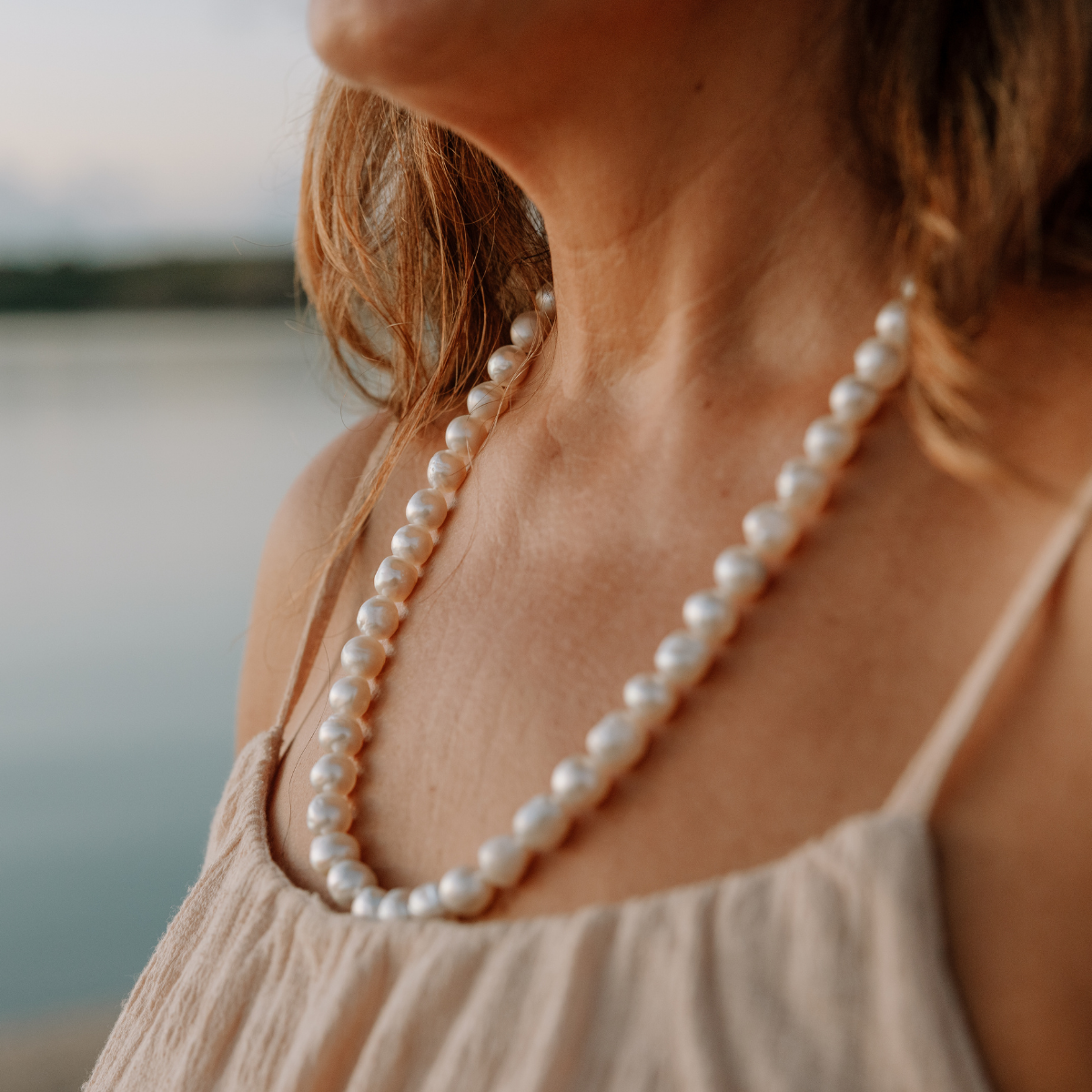 Pearl necklace worn by a person with a blurred natural background