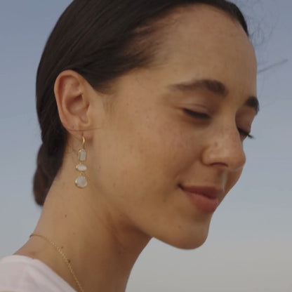 A woman wears her unique Radiance Medley Drop Hook Earrings that feature our Cygnet Bay grown Mother of pearl shell that has been faceted to resemble traditional diamond cuts like emerald cut, oval cut and pear cut and set in a bezel frame.