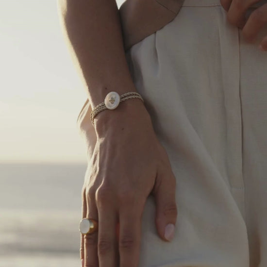 A woman wears her stunning Mother of Pearl button bracelet that features a silk cord rope and Mother of Pearl button motif.
