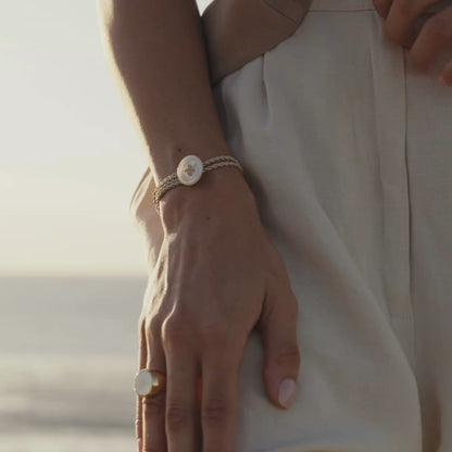 A woman wears her stunning Mother of Pearl button bracelet that features a silk cord rope and Mother of Pearl button motif.