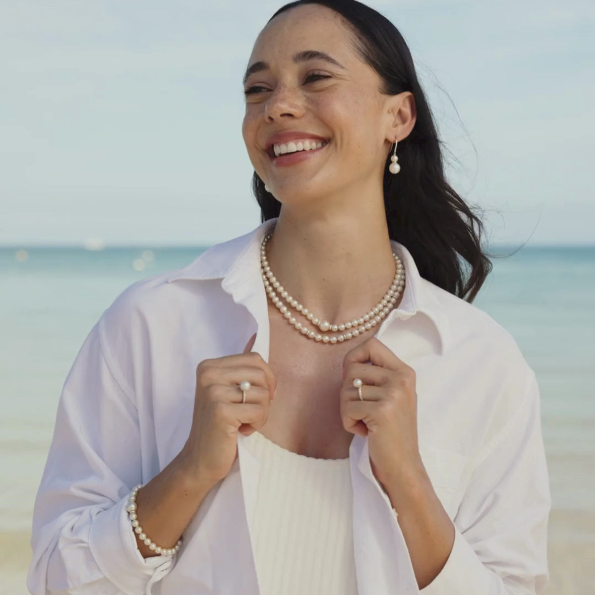A woman wears her Eternal Diamond Pearl Jewellery pieces, including a pair of hooks, pearl strand necklaces, a pearl strand bracelet and pearl rings all featuring our Australian grown South Sea and Akoya pearls set alongside stunning white diamonds.
