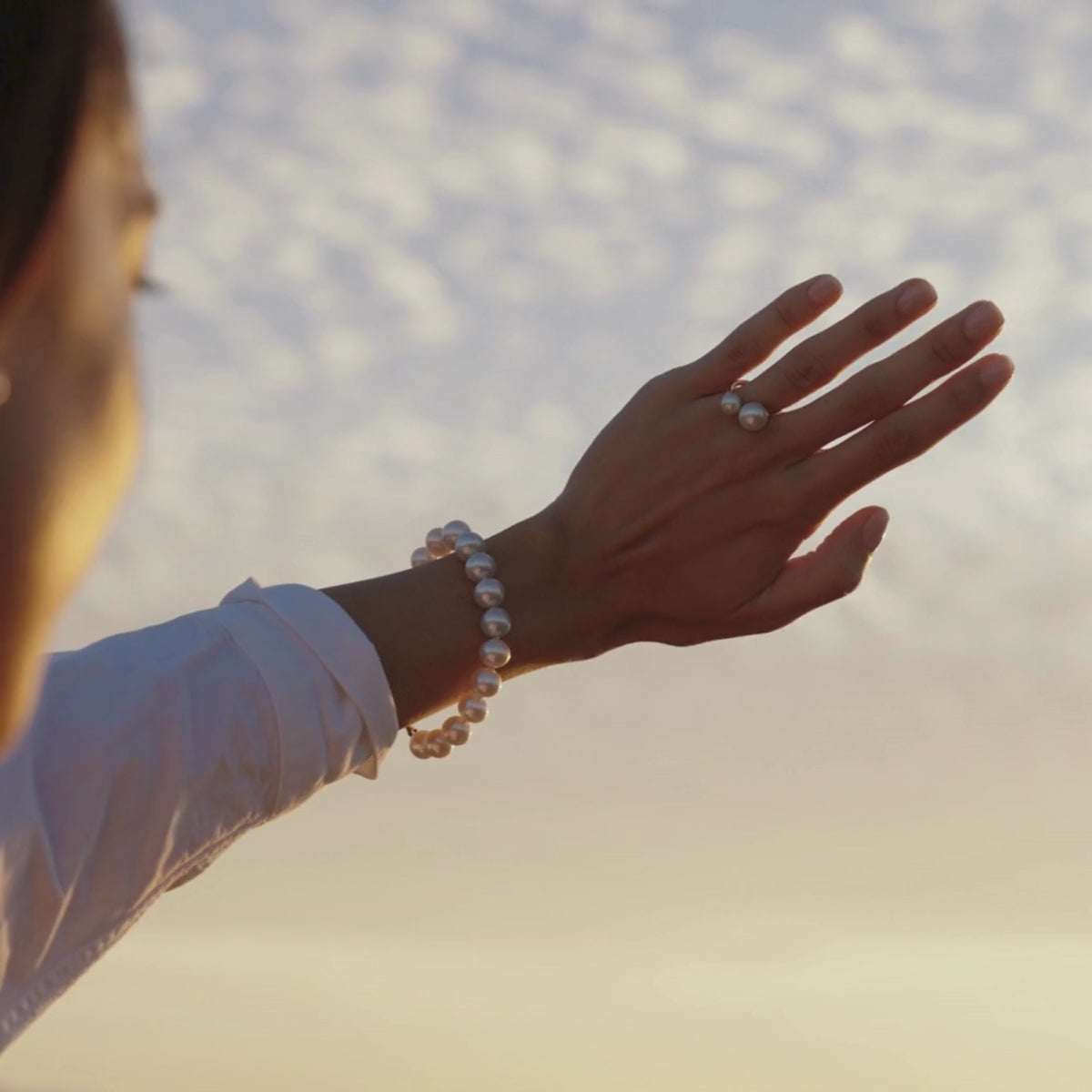 A woman wears her stunning Provenance Open Pearl Ring that features both our Australian South Sea and Akoya pearls set alongside each other, and around her wrist she wears a stunning Australian South Sea pearl strand bracelet that shines with its natural colour and lustre.