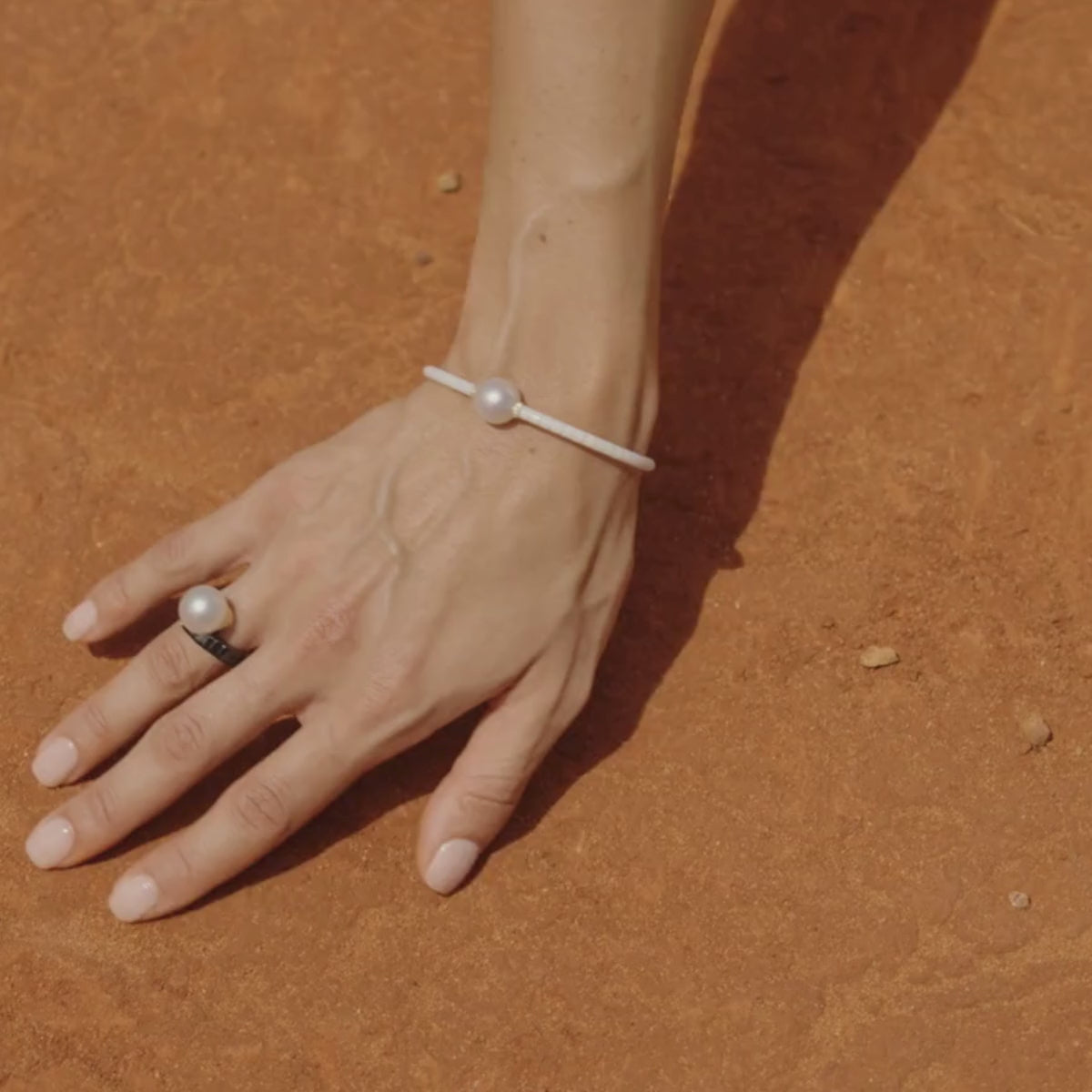 A woman wears her white Terra Ceramic Pearl bracelet with a matching black ring, both featuring our Australian grown South Sea pearls grown at our very own Cygnet Bay Pearl Farm in WA.
