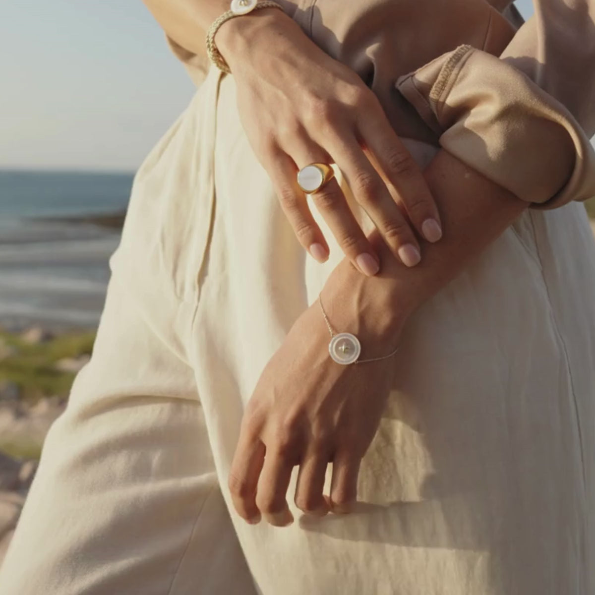 A lady wears her beautiful Mother of Pearl Button Chain Bracelet with an Ebb Mother of Pearl Ring while looking over at our Cygnet Bay Pearl Farm where our mother of pearl shell is sustainably grown.