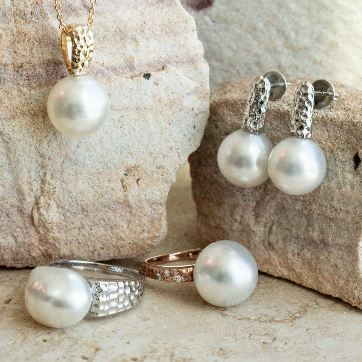 Pearl jewelry set including necklace, earrings, and rings on a stone surface