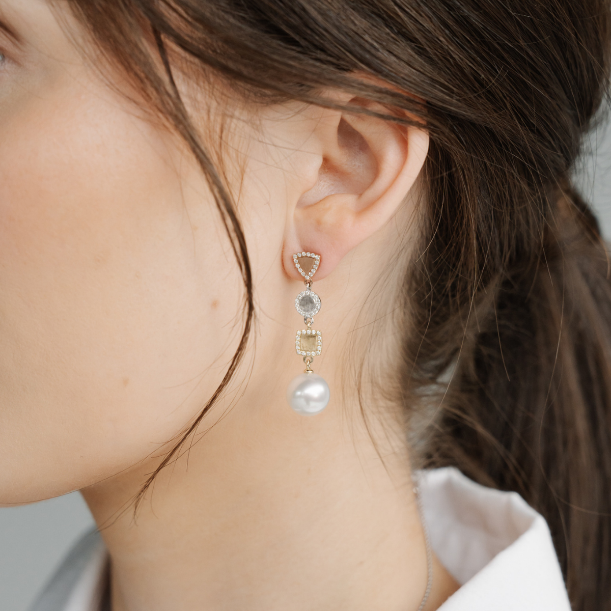 Close-up of an ear wearing a pearl earring with a blurred background